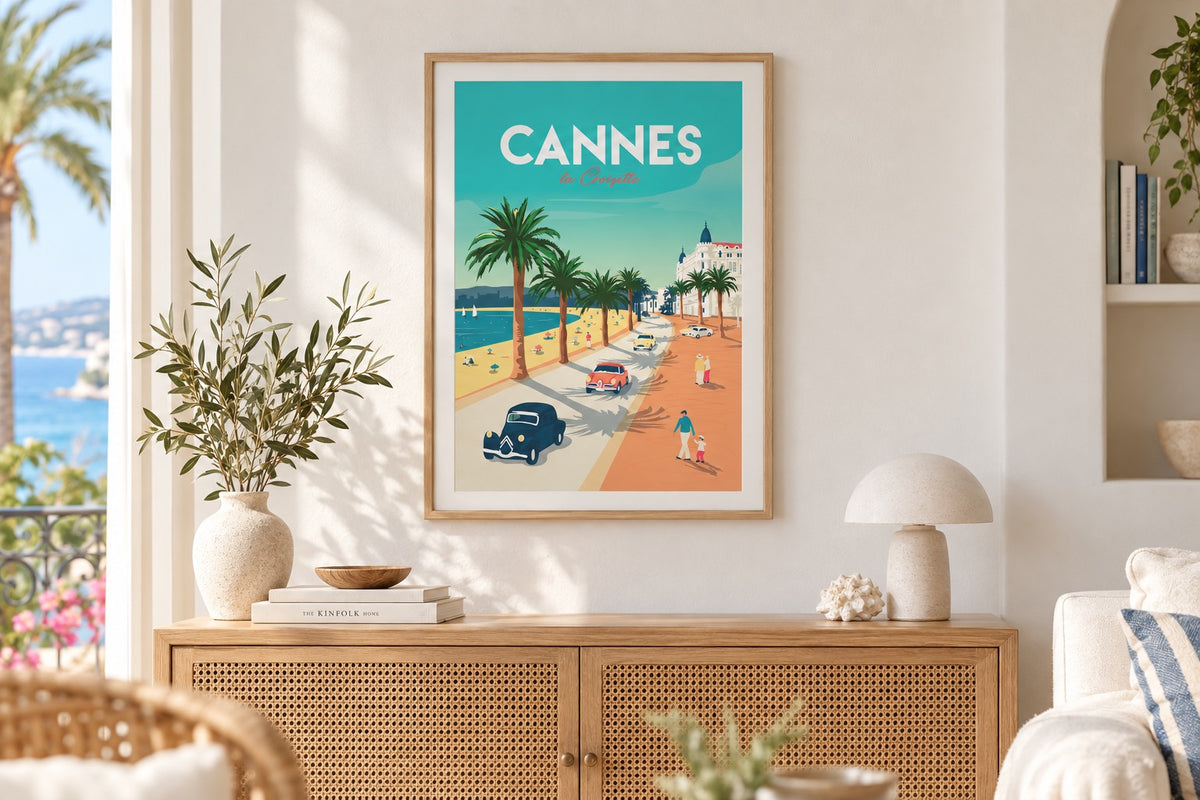 Affiche Cannes La Croisette encadrée au-dessus d'un buffet cannage dans un salon blanc