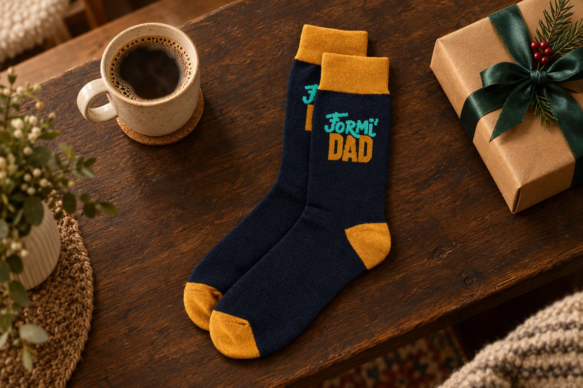 Chaussettes Formi'Dad bleu nuit et orange posées sur une table avec une tasse de café