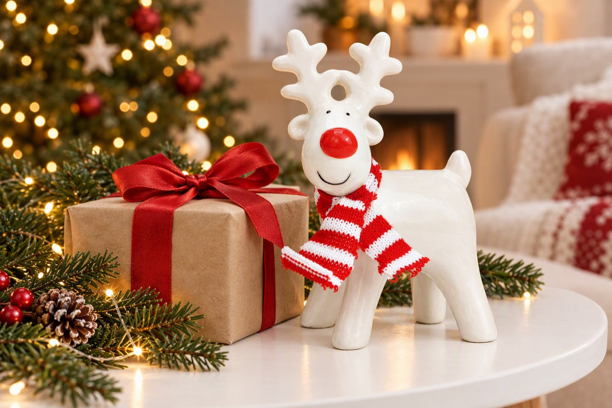 Renne de Noël en céramique PM blanc et rouge posé dans une décoration de fêtes
