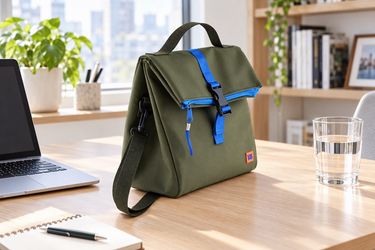 Sac isotherme Yunik vert et bleu posé sur un bureau moderne