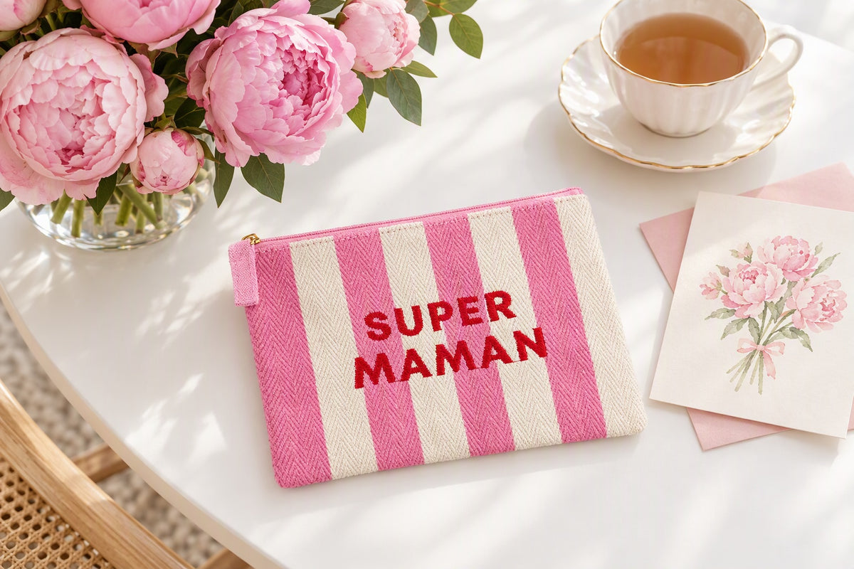 Trousse Super maman rayée rose et blanc posée sur une table avec un bouquet de fleurs