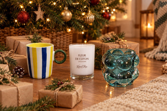 Petits cadeaux de Noël emballés en papier kraft avec bougie, mug et photophore au pied d'un sapin