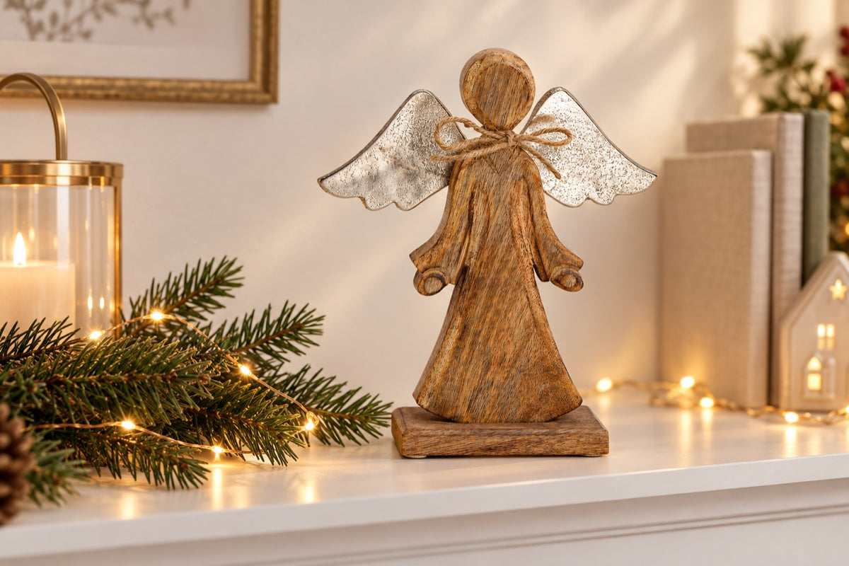 Ange de Noël naturel et argent sur socle posé sur une étagère avec guirlande lumineuse