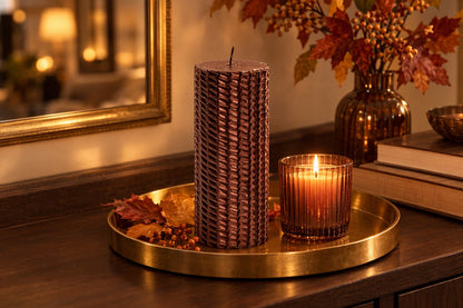 Bougie cylindrique marron pailletée allumée sur un plateau doré