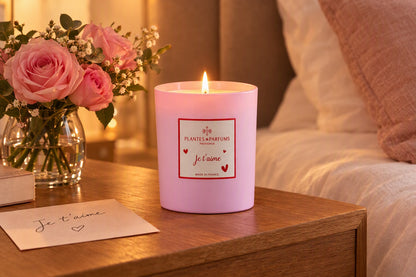 Bougie Je t'aime allumée sur une table de chevet avec des roses et un mot doux