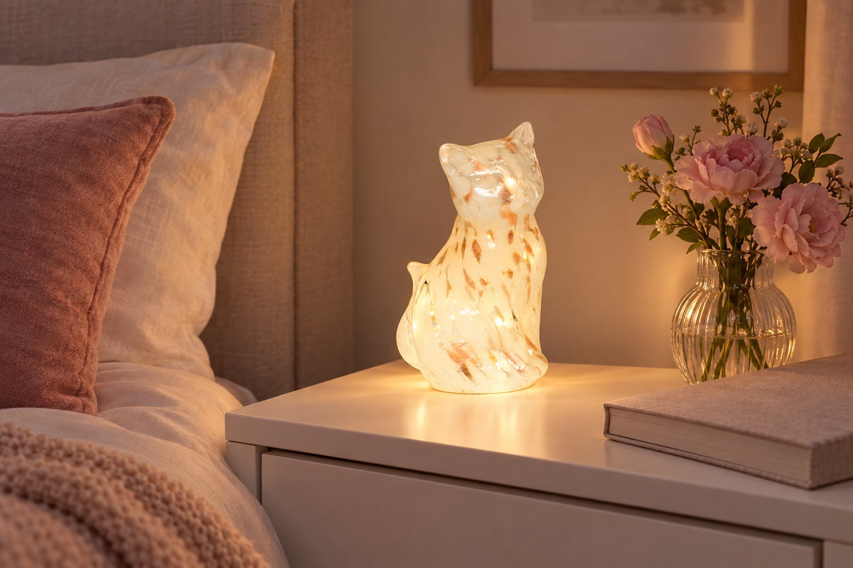 Chat lumineux LED en verre moucheté allumé sur une table de chevet