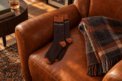 Chaussettes Le beau gosse marron et orange posées sur un fauteuil en cuir