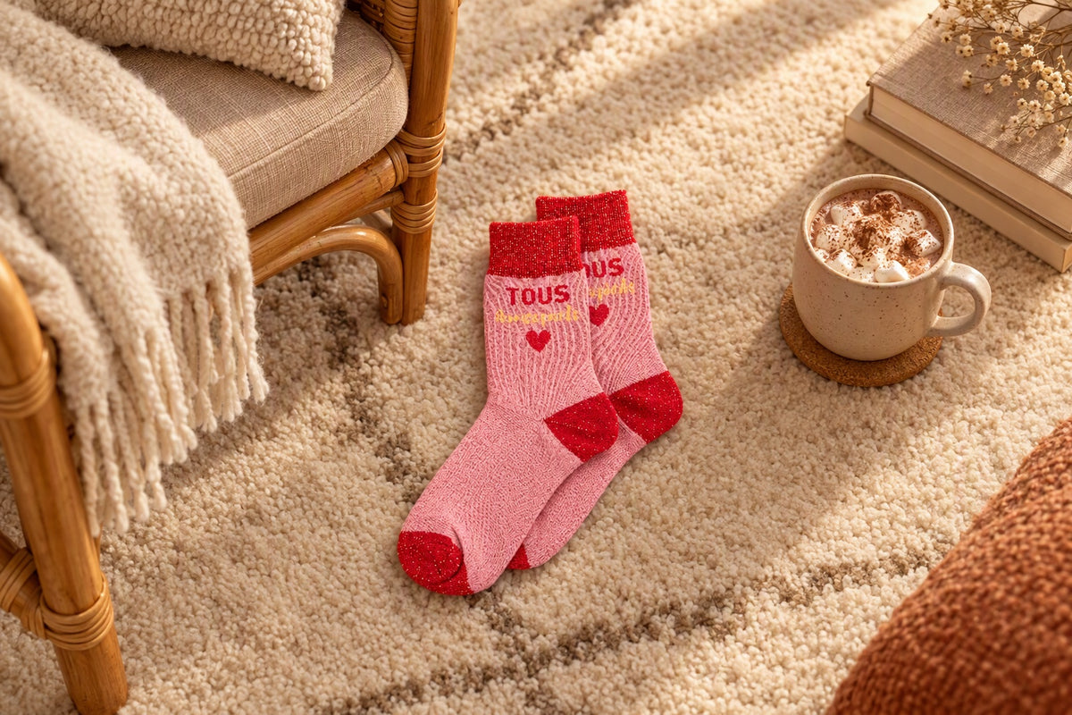 Chaussettes Tous à mes pieds rose et rouge posées sur un tapis près d'un fauteuil