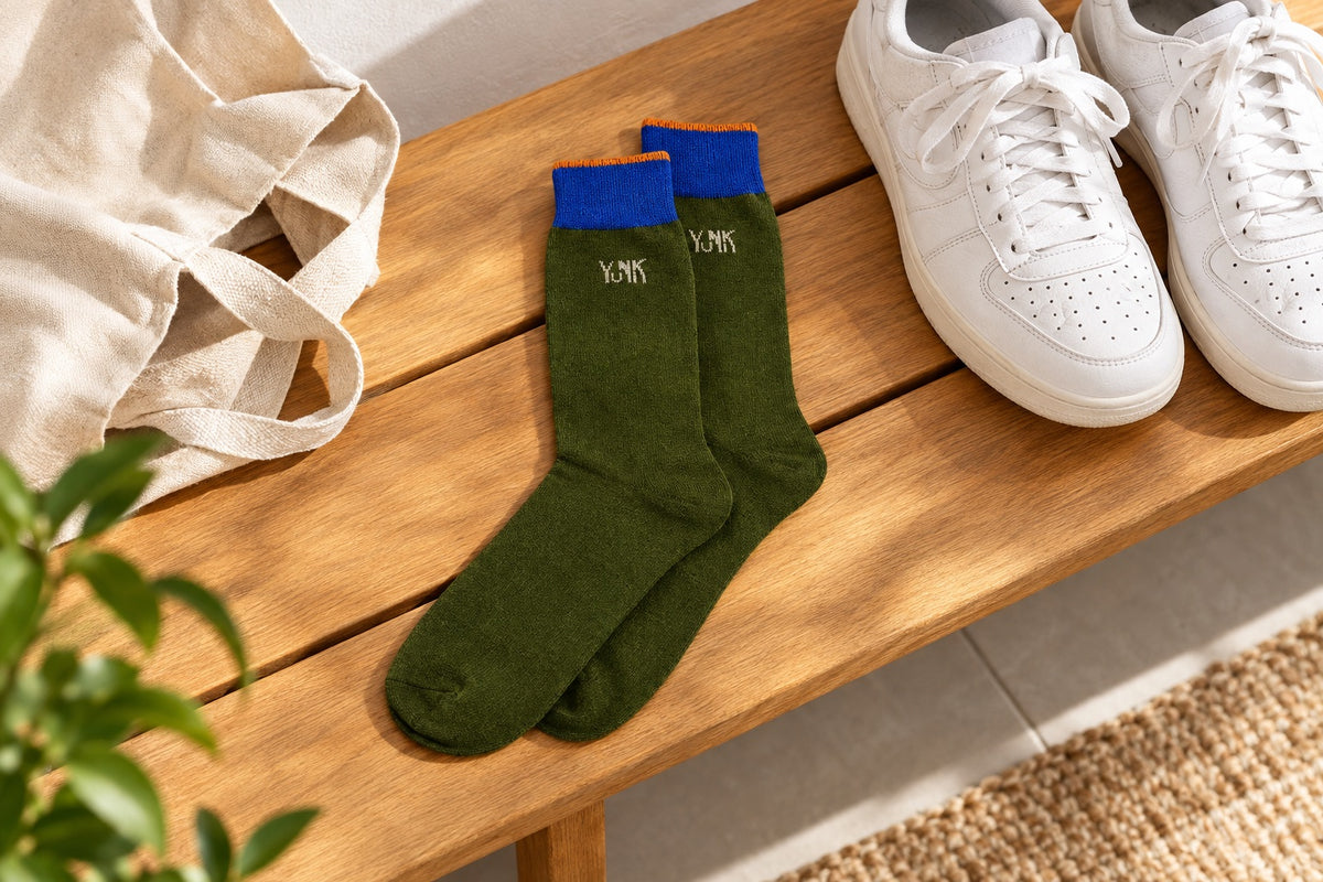 Chaussettes Yunik vertes et bleues posées sur un banc en bois