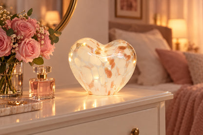 Cœur lumineux LED en verre moucheté rose doré allumé sur une commode