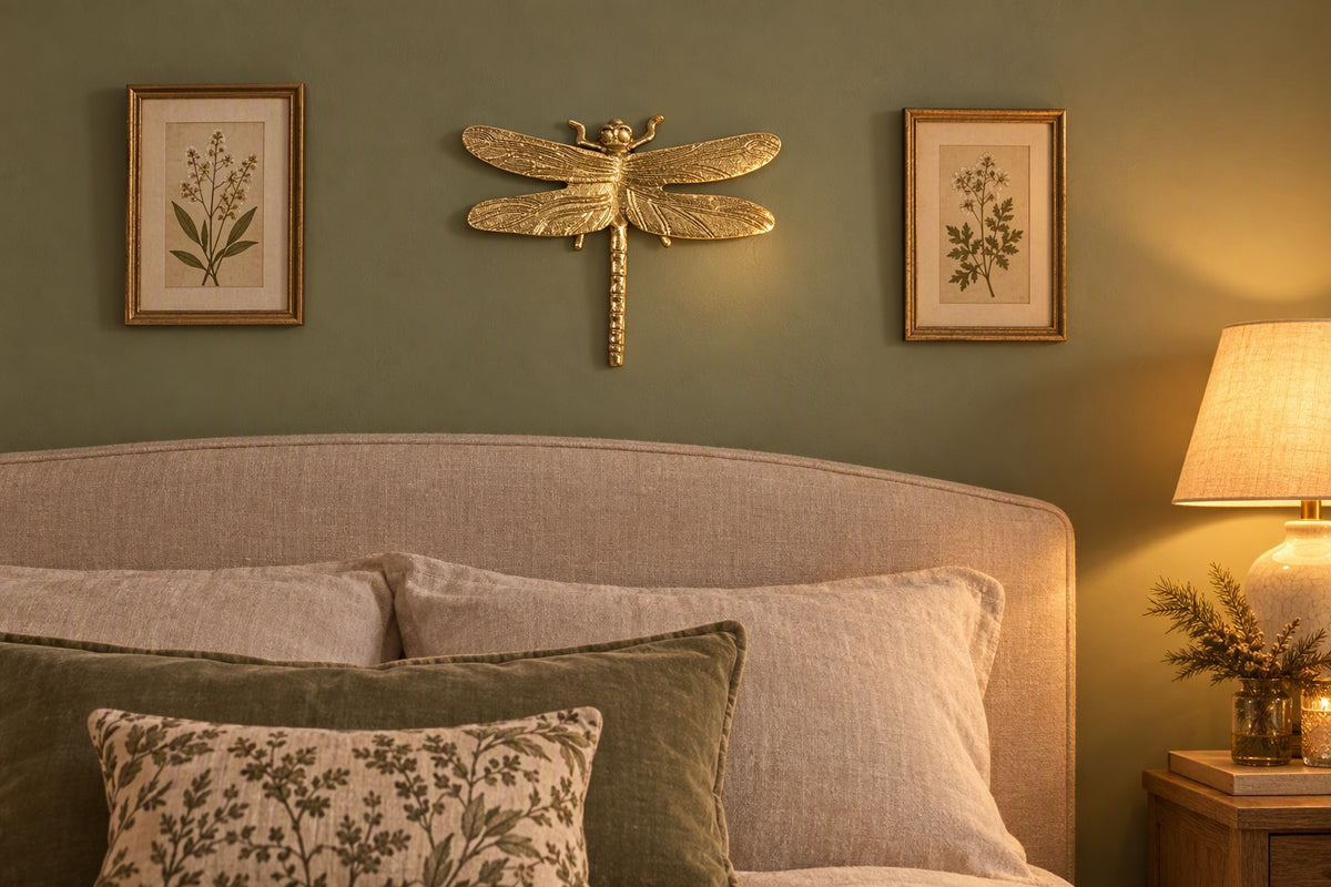 Libellule dorée en métal en déco murale au-dessus d'un lit dans une chambre vert sauge