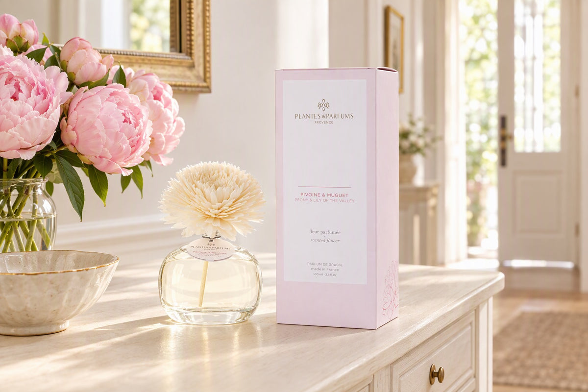 Diffuseur de parfum fleur pivoine et muguet posé sur une console d'entrée avec un bouquet de pivoines