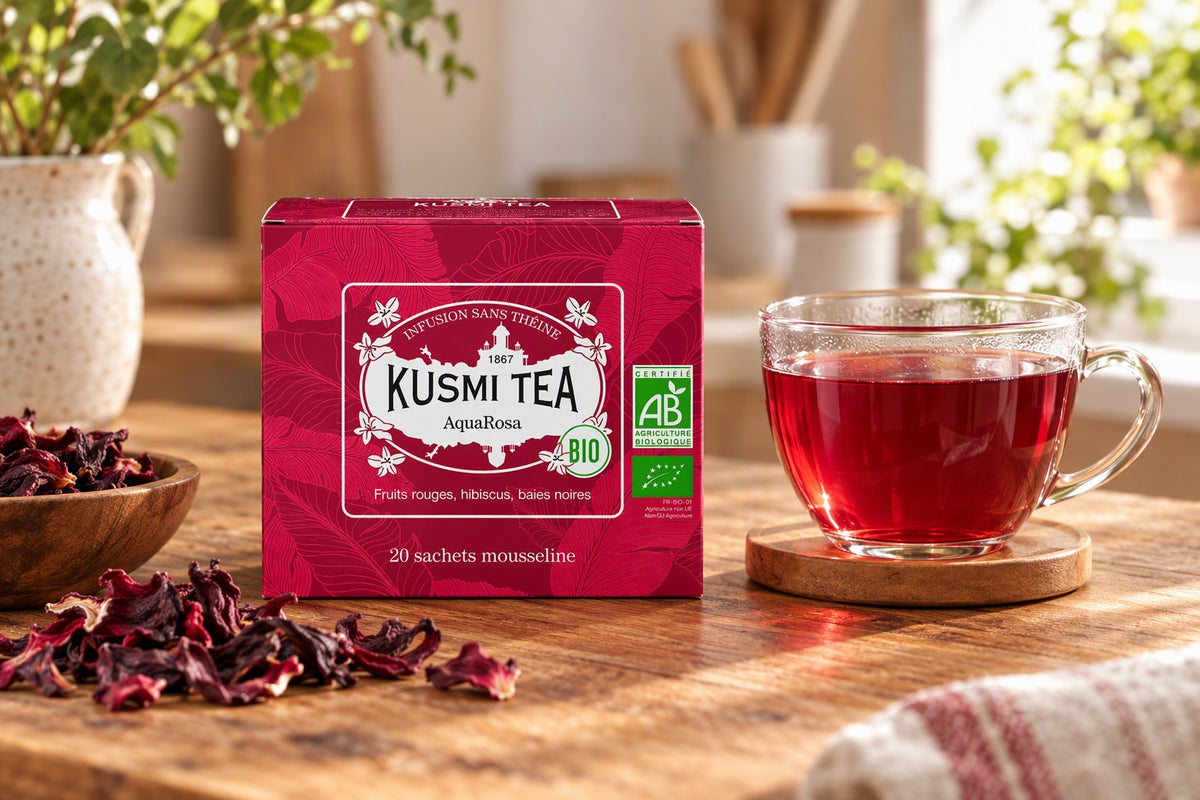 Tasse d'infusion hibiscus rouge à côté d'une boîte Kusmi Tea AquaRosa sur une table