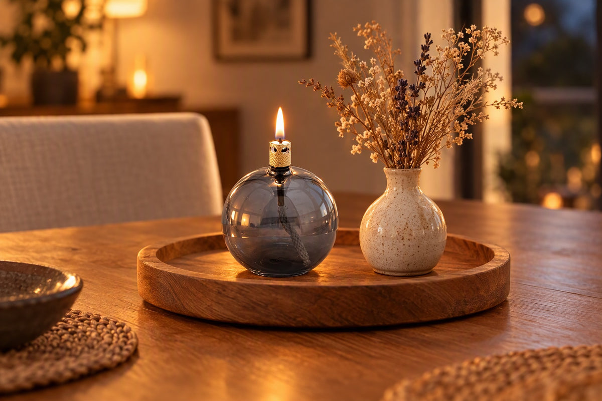 Petite lampe à huile ronde en verre gris allumée sur un plateau