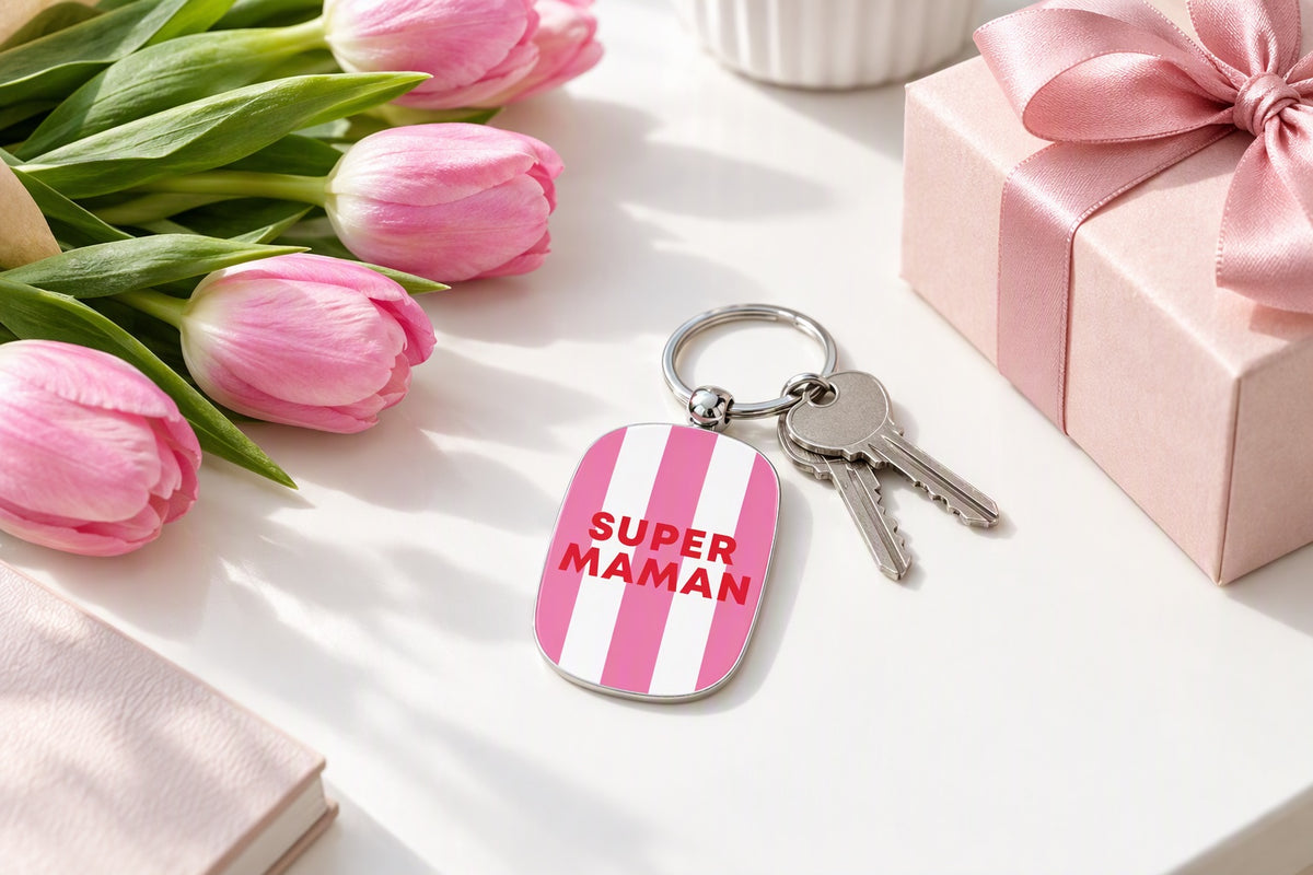 Porte-clés Super maman rose et blanc avec des clés posé près d'un bouquet de fleurs