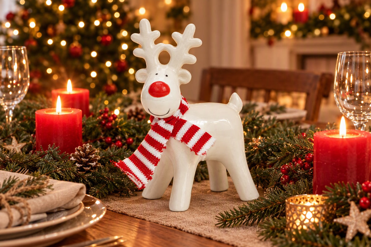 Renne de Noël en céramique MM blanc et rouge posé dans une décoration de fêtes