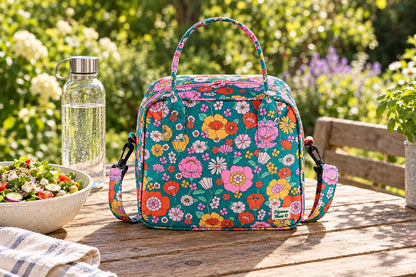 Sac isotherme à fleurs vert multicolore posé sur une table de pique-nique