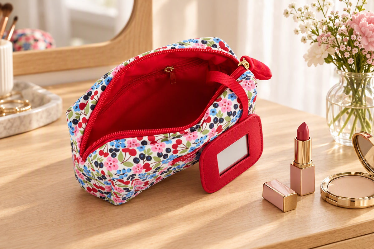 Trousse à maquillage imprimé cerises avec miroir posée sur une coiffeuse