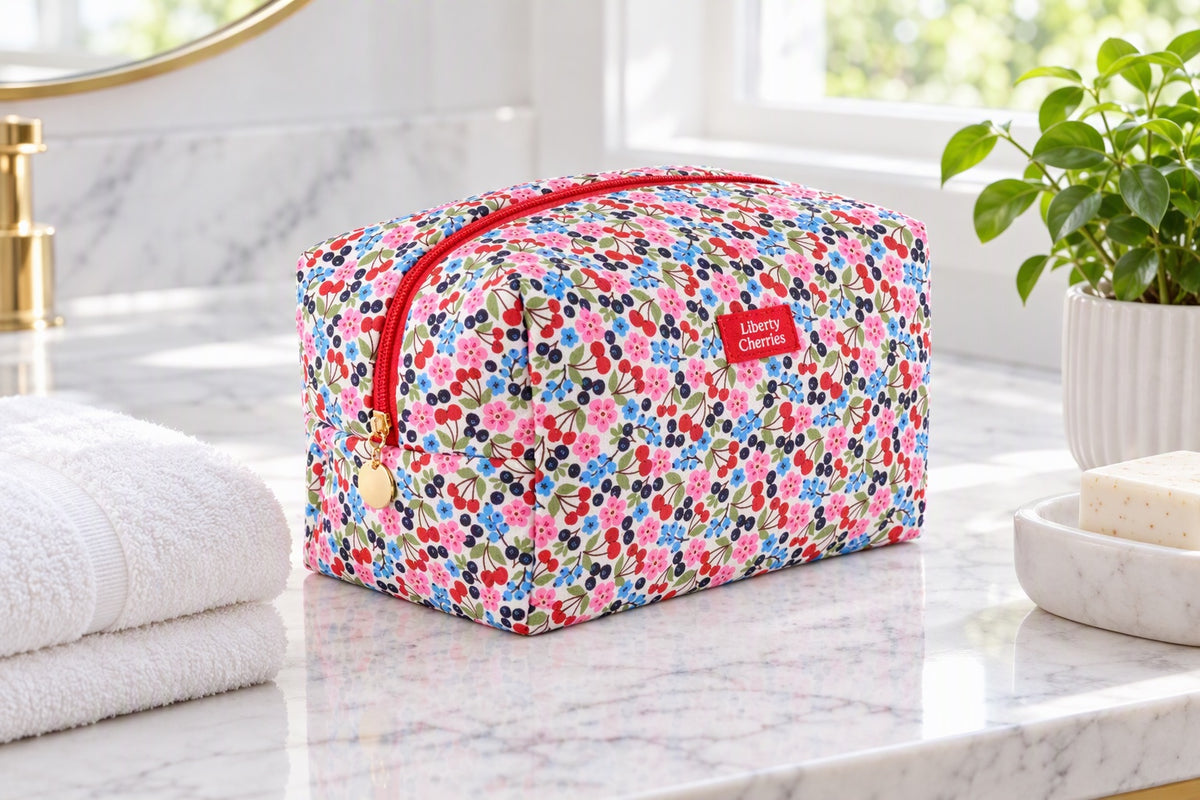 Grande trousse de toilette imprimé cerises posée dans une salle de bain lumineuse
