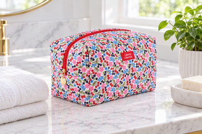 Grande trousse de toilette imprimé cerises posée dans une salle de bain lumineuse