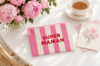 Trousse Super maman rayée rose et blanc posée sur une table avec un bouquet de fleurs