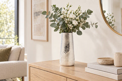 Vase argenté en aluminium martelé avec un bouquet d'eucalyptus sur une console