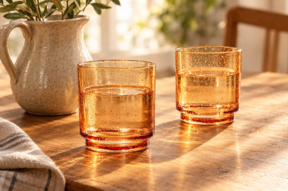 Verres empilables ambre remplis d'eau sur une table en bois au soleil